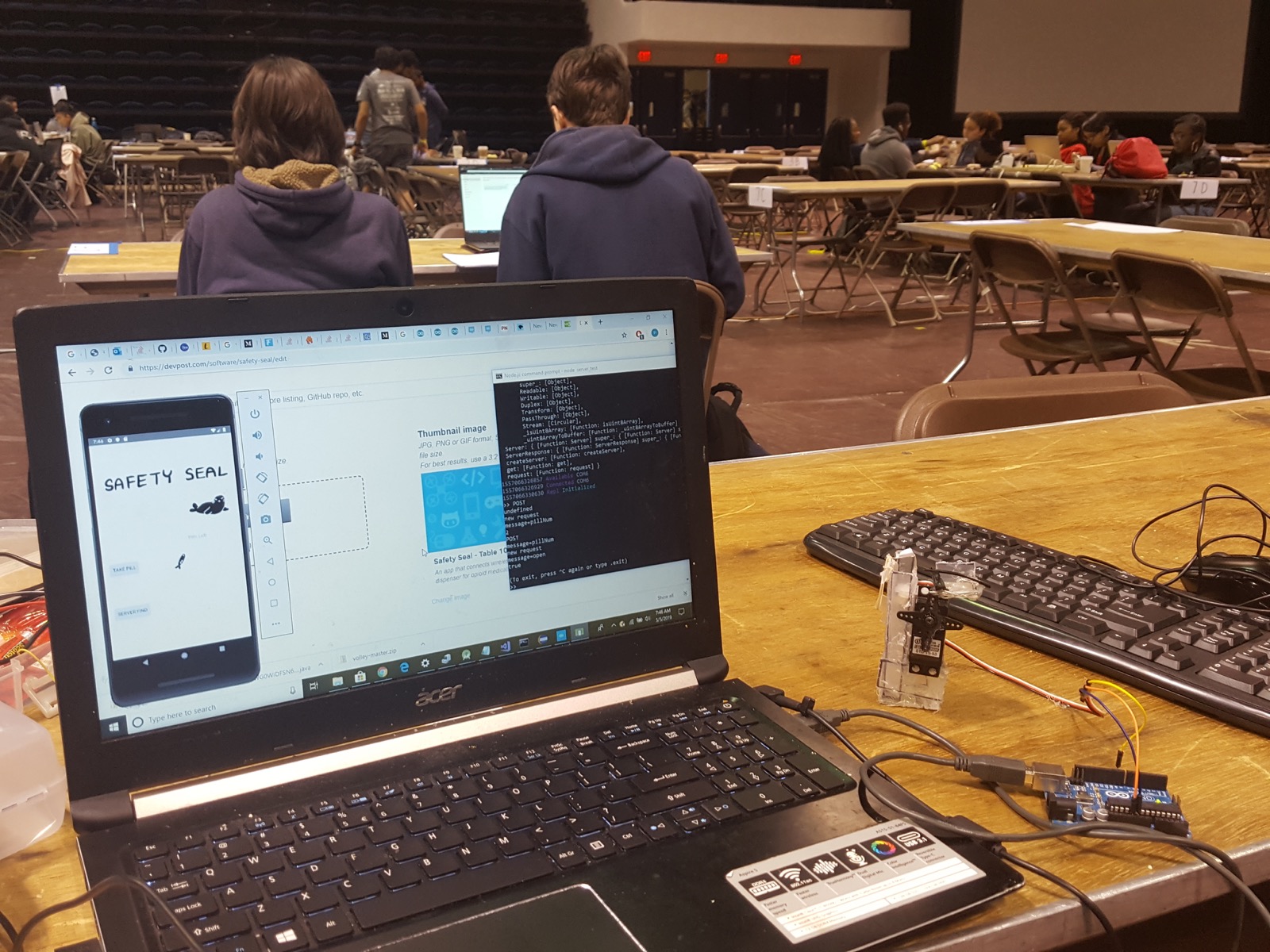 Safety Seal's app on a laptop alongside the Arduino and servo-controlled pill dispenser prototype.
